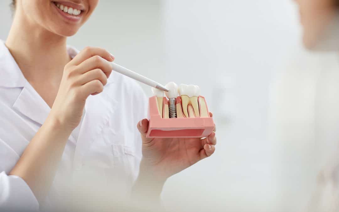 dental hygienist pointing to dental implant care with dental patient at Pristine Dental Care